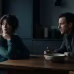 A woman looking distressed and thoughtful during a difficult conversation with a partner in a modern kitchen.