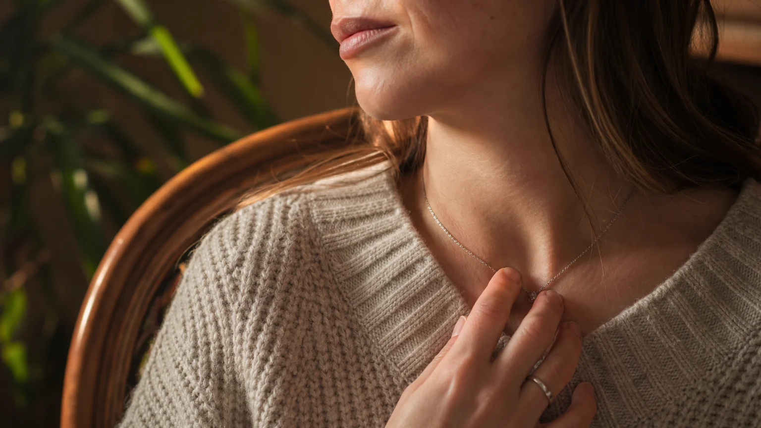 A close-up photo of a hand touching the base of the neck in a comforting, self-soothing gesture during a moment of stress.